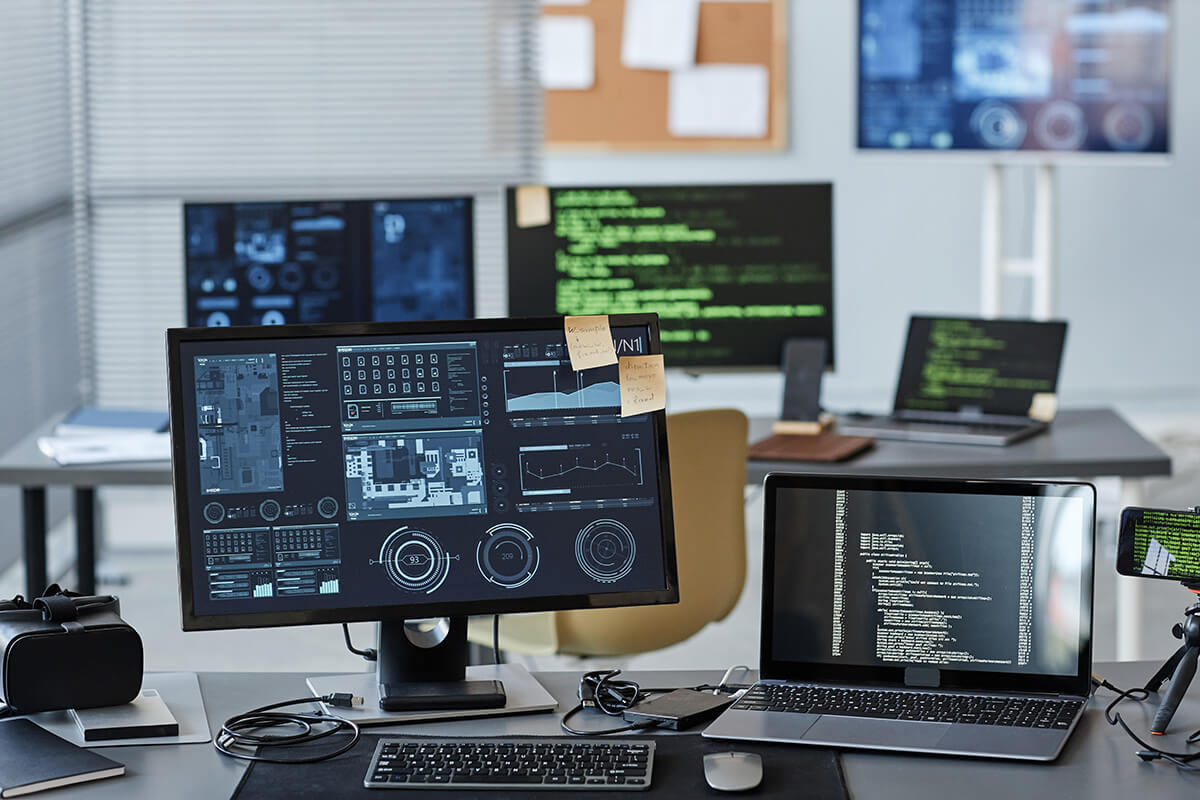 Modern office workspace with multiple computer monitors displaying data and code.