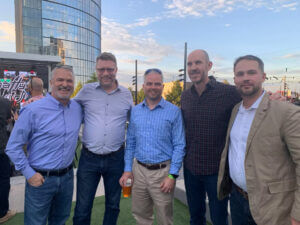 Group of five men posing together outdoors