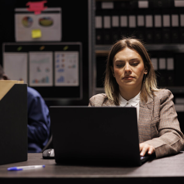  Women working on a criminal investigation, sitting at a desk typing on a laptop.