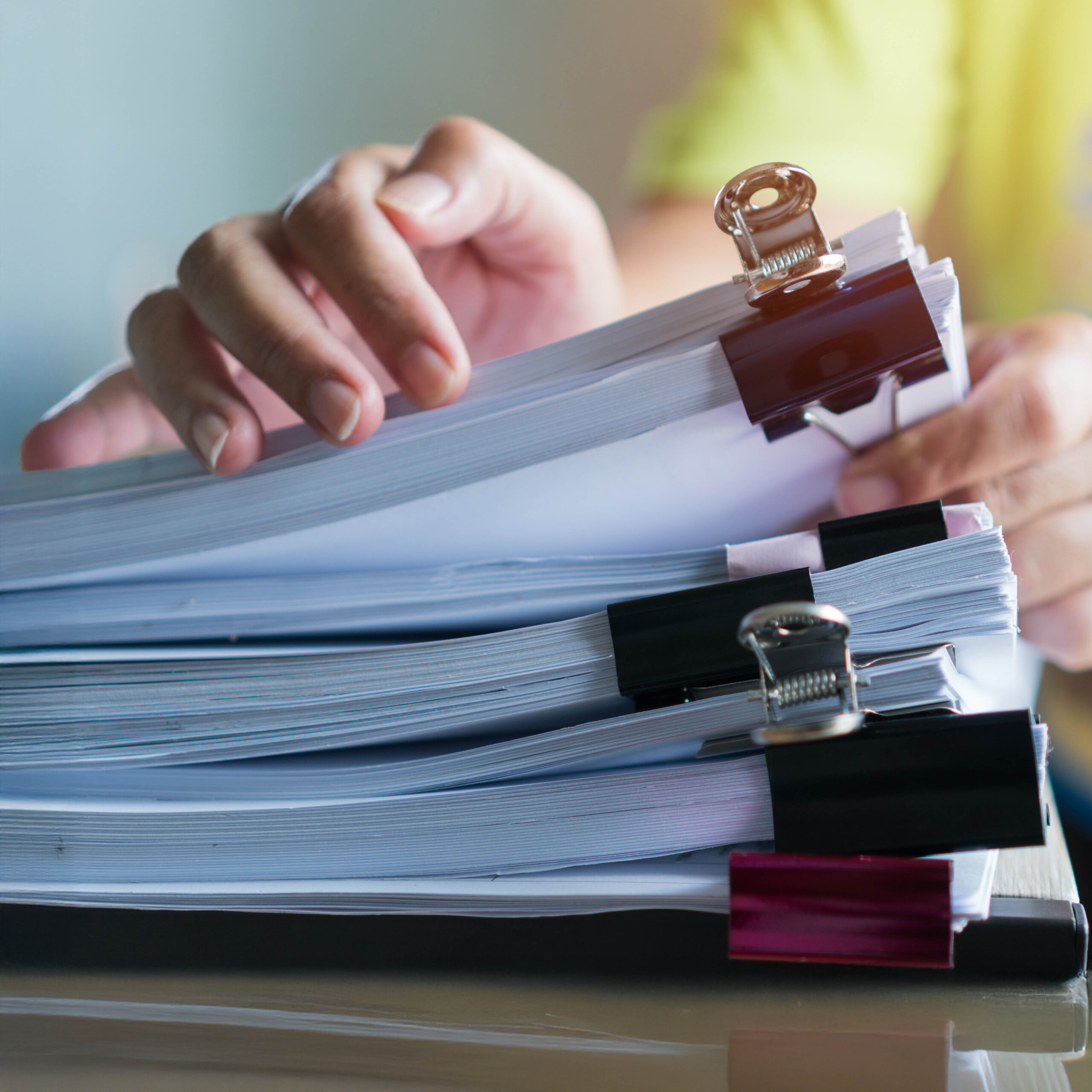 A stack of documents held together with clips being sorted through.