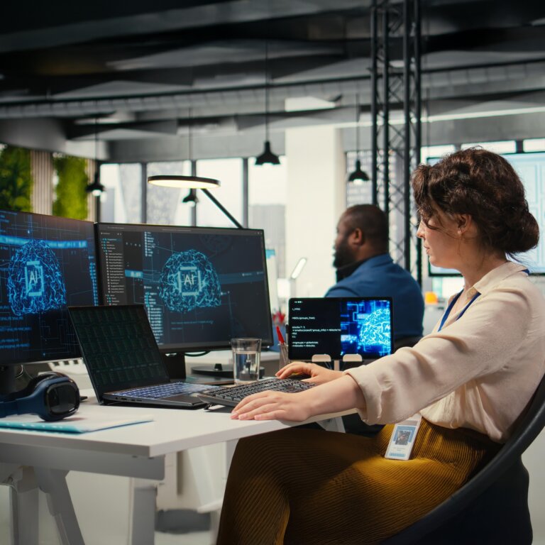  Coworkers sitting at desks working on desktops with security displays.
