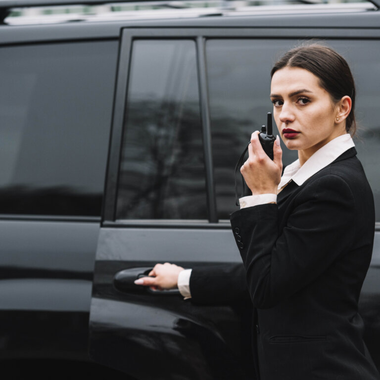  An executive protection professional coordinating security while opening the door of a vehicle.